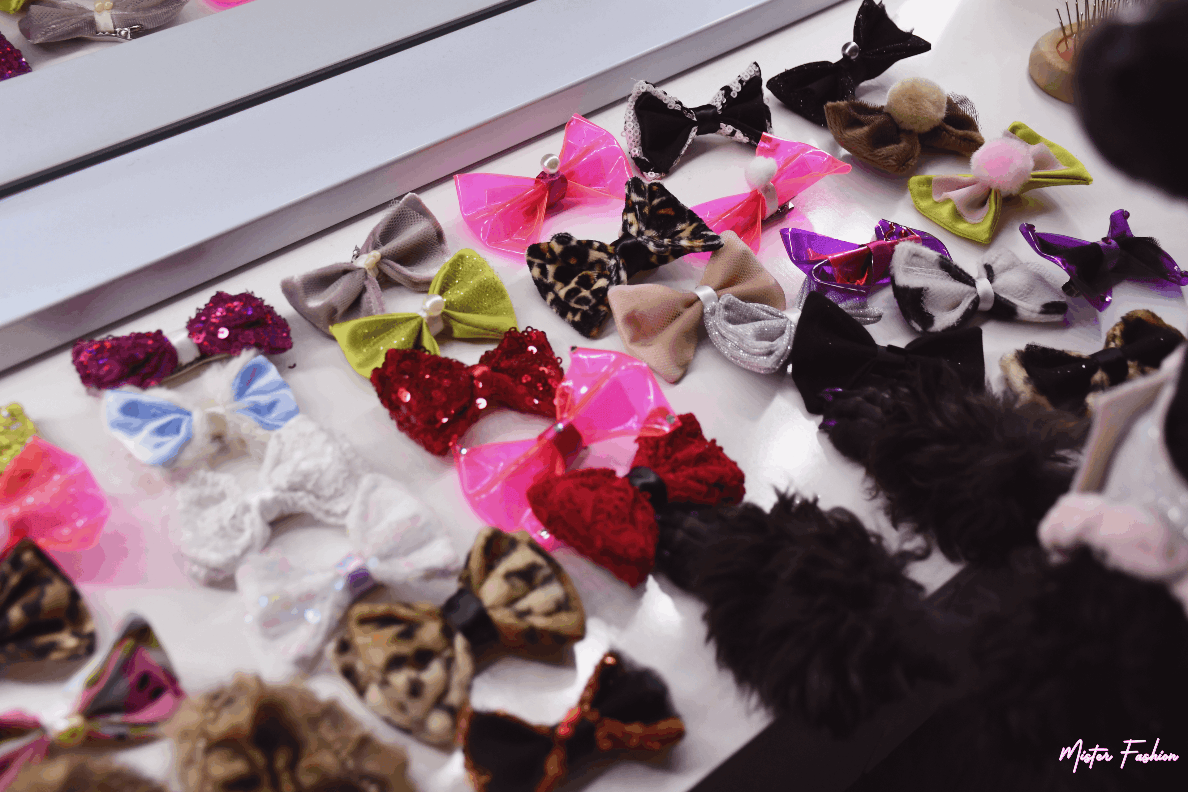 Aura the poodle shows her paws with purple nail polish. Many pet hairbows surround her paws. 