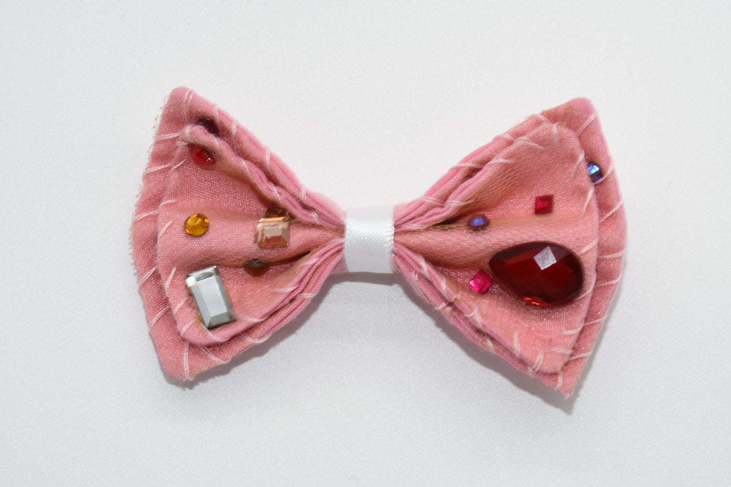 a pink hairbow can be seen with multicolor stones