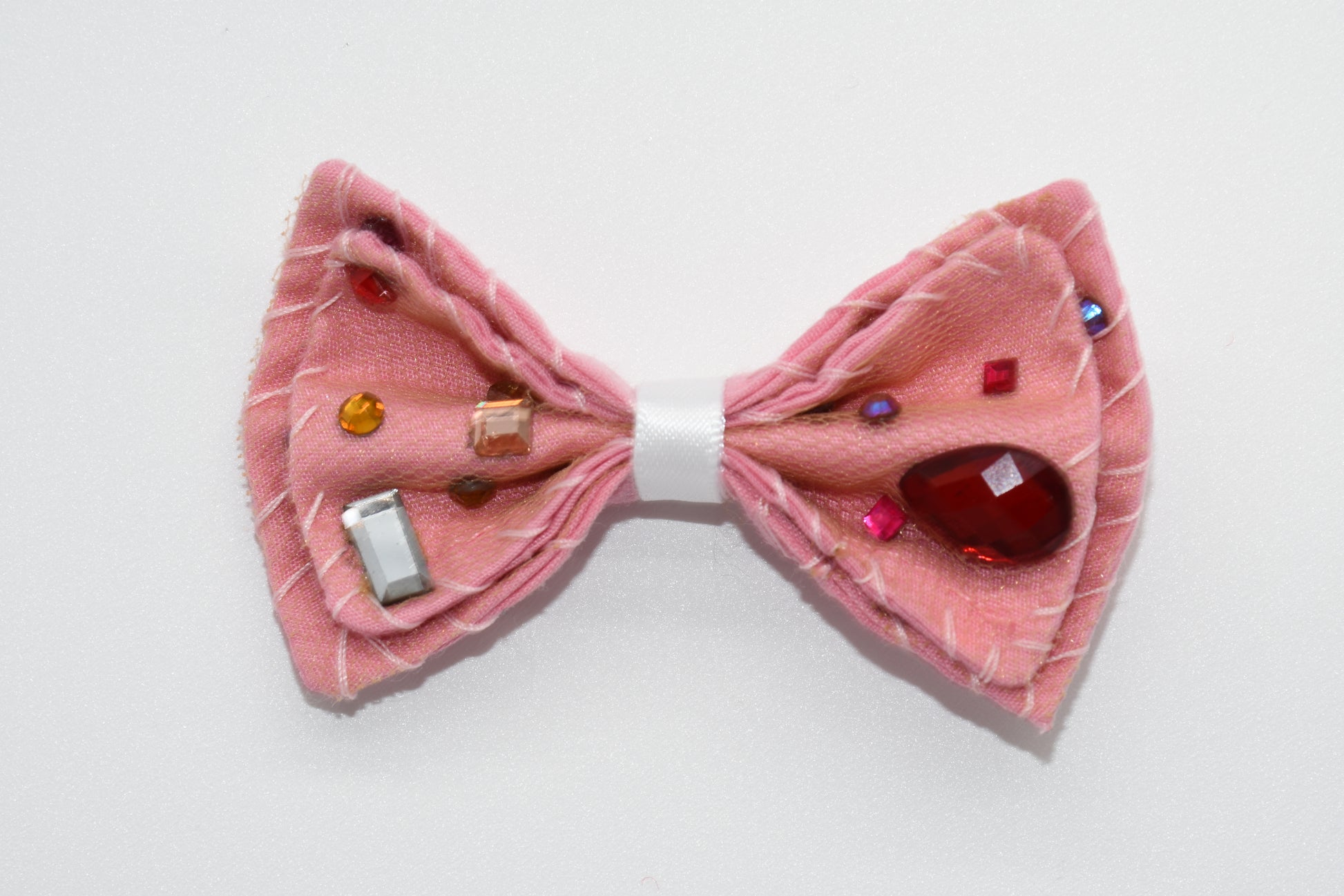 a pink hairbow can be seen with multicolor stones